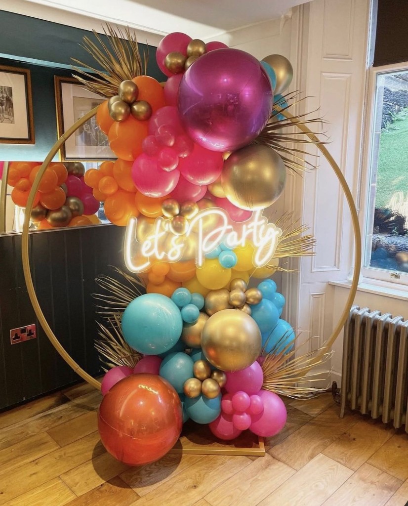 Gold hoop balloon display with a Let's Party neon sign