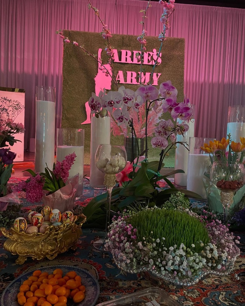 Outdoor event décor with florals, palms, and a script neon sign