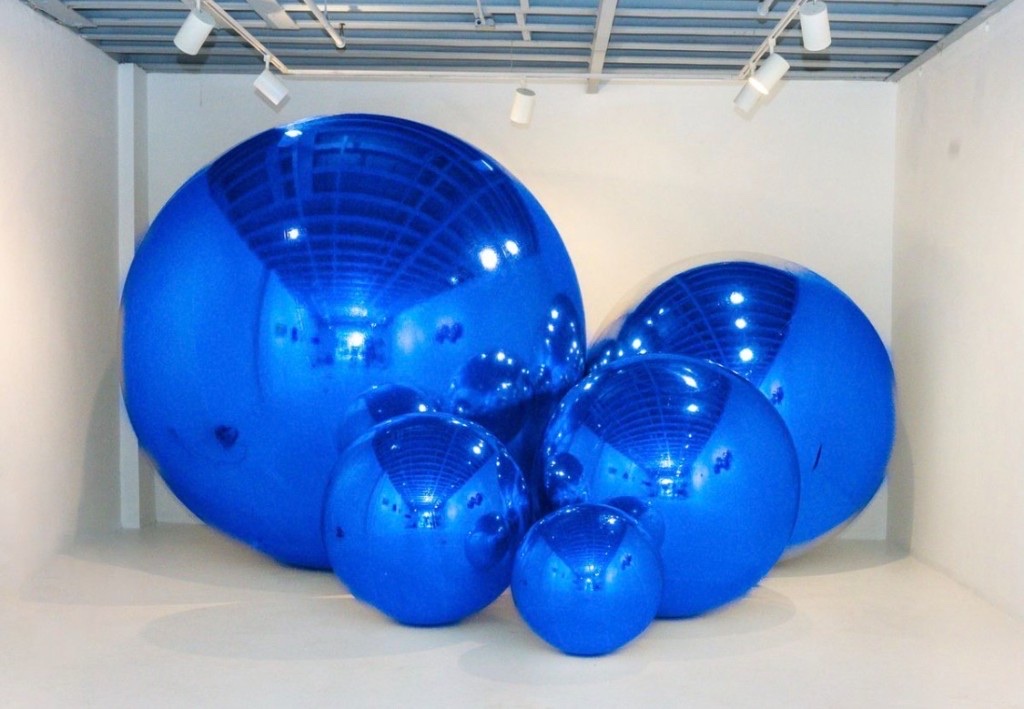 Reflective royal blue sphere sculptures in a white gallery installation