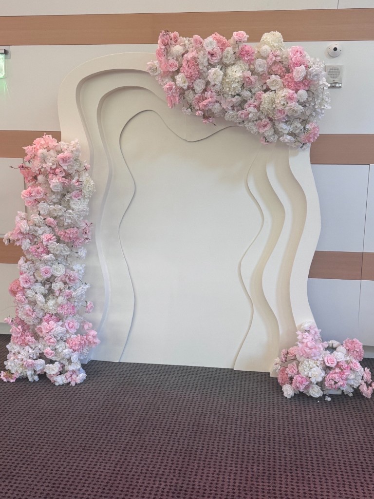 Wavy white layered backdrop with pink and white floral clusters